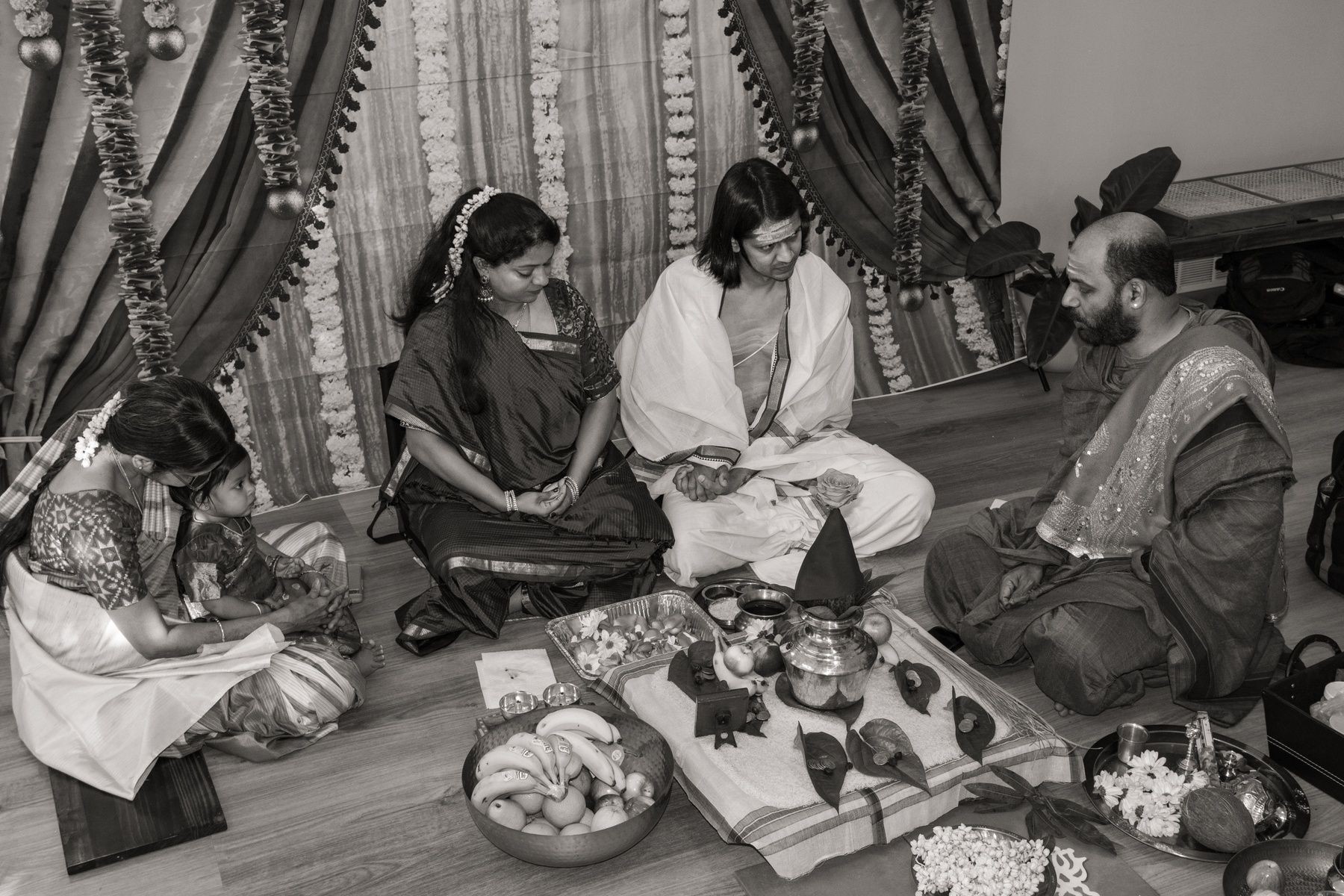 People participating in a traditional Indian ceremony with offerings, wearing traditional attire.